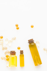 Natural cosmetics concept, essential oil in glass bottles and vitamin pills, white background, close up, top view