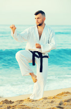 Joyful guy practising karate kata poses