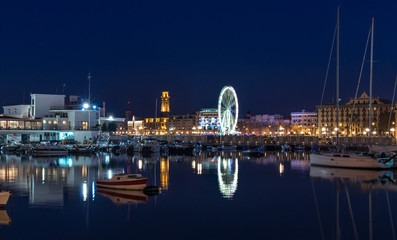 Bari seafront night Citylights cityscape. Ferris Wheel on coastline at twilight