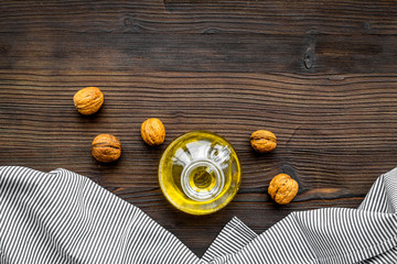 Oil as cosmetics. Walnut oil near walnut in nutshell on dark wooden background top view copy space