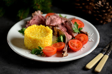 Medium rare rack of lamb with boiled rice and a salad of cherry tomatoes.