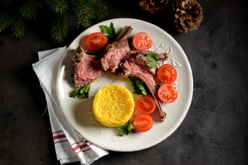 Medium rare rack of lamb with boiled rice and a salad of cherry tomatoes.