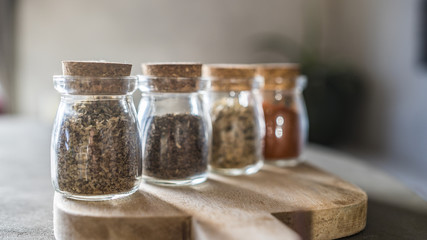 Fototapeta na wymiar Herbs and Spices in Jars on Wooden Board
