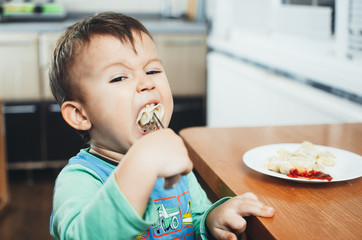 A hungry child is eating dumplings in the kitchen