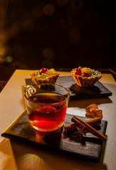 cup of tea with a cake, cinnamon and anise on tray and a black background