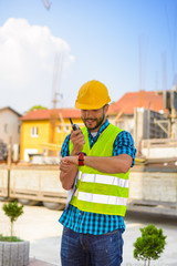 Workers in hardhat and green jacket posing on building site