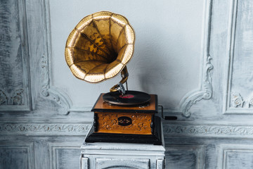 Old record player against ancient wooden wall. Antique gramophone with retro plate produces...