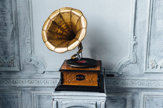 Old record player against ancient wooden wall. Antique gramophone with retro plate produces pleasant sounds or music. Stereo system. Revolution and sound technology concept