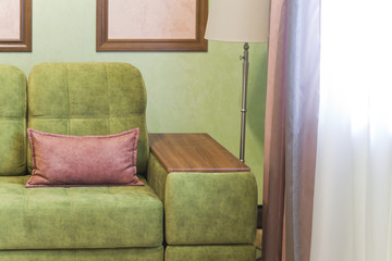 Фрагмент интерьера с зеленым диваном и розовыми элементами