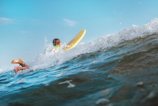 Boy floats on surf board over the wave crest
