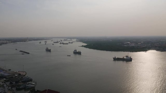 Aerial view of tugboat and Cargo transport ship passing industrial port area in river. at sunset time.