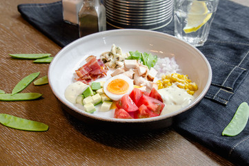 Healthy Hearty Cobb Salad with Chicken, Bacon, Tomato, Onions, Eggs, green beans. American food. Close up, home made