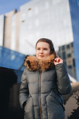 Office place with girl stand near building. Smiling girl look at camera and around with pretty face. Office worker break, winter time.