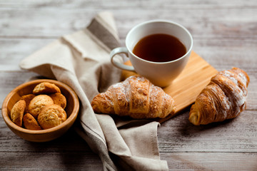 breakfast with tea and croissant on a white wooden background