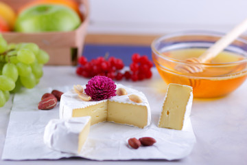 Camembert with honey, red berries and apples, cheese with green grapes, peanuts and pink flower, healthy food, French breakfast with brie in retro style