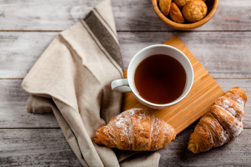 breakfast with tea and croissant on a white wooden background