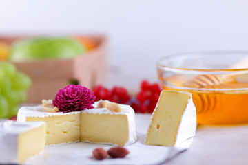 Camembert with honey, red berries and apples, cheese with green grapes, peanuts and pink flower, healthy food, French breakfast with brie in retro style