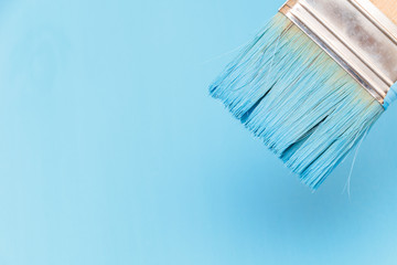Staining the wooden surface with blue paint using a paint brush
