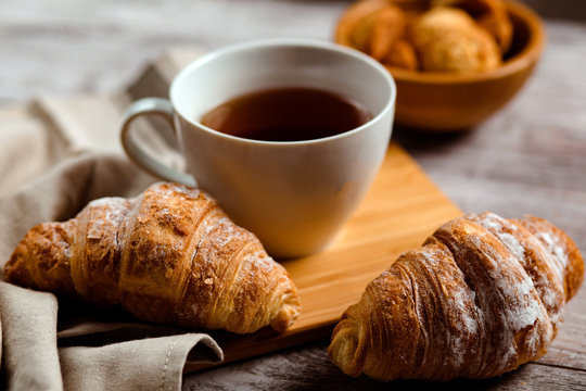 breakfast with tea and croissant on a white wooden background