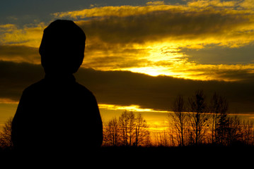 Fototapeta premium silhouette of a little boy in a cap on the sunset
