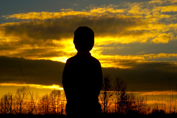 silhouette of a little boy in a cap on the sunset
