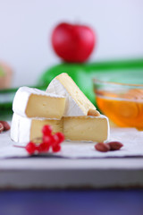 Camembert with green grapes, honey with brie cheese, green bottle in the background, red berries and pink flower, peanuts, healthy food, French breakfast with brie cheese