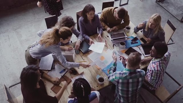 Business meeting at modern office. Top view of multiracial group of people working near the table together. Slow mo