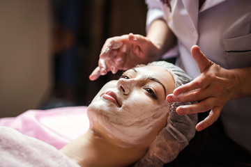 Obraz na płótnie Canvas woman getting facial care peeling mask by beautician at spa salon