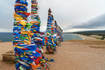 Wooden ritual pillars with colorful ribbons Hadak on cape Burkhan. Lake Baikal. Olkhon Island....