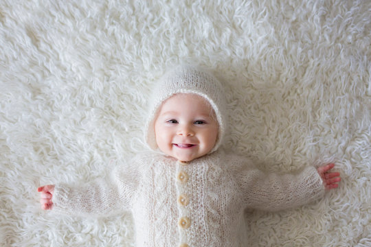 Close portrait of a little baby boy in white knitted onesie and a hat