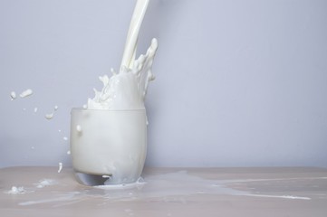 Milk being poured into a glass from a height and splashing back out