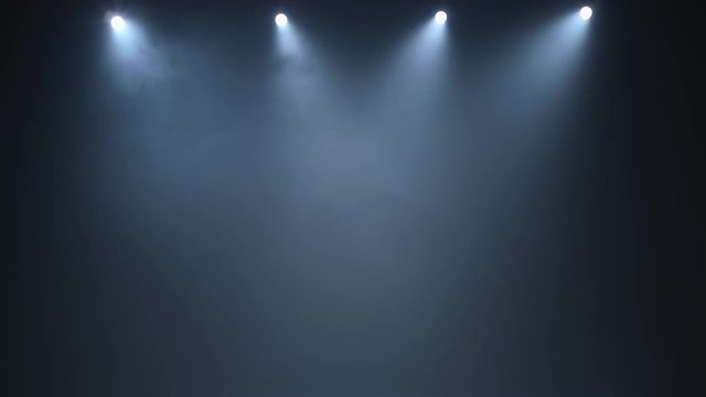 Four white spotlights illuminate dark smoky concert hall
