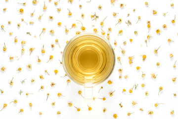 Cup of herbal chamomile tea with camomile dry blossoms  on a white background.