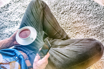 closeup cup of tea hands with smartphone at home office 