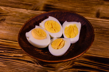 Ceramic plate with peeled boiled eggs on wooden table