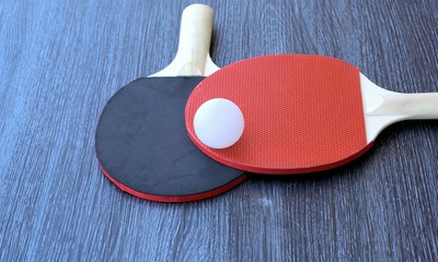 White ball and pair of table tennis rackets or White ball and pair of ping pong rackets.