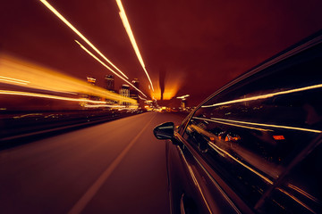 View from Side of Car moving in a night city, Blured road with lights with car on high speed. Concept rapid rhythm of a modern city.