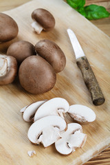 Braune Champignons mit Messer auf Holzbrett 