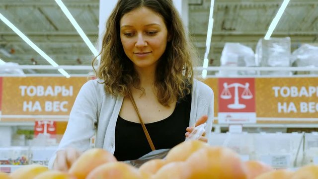 Beautiful girl picks fruit in a vegetable shop, 4k.