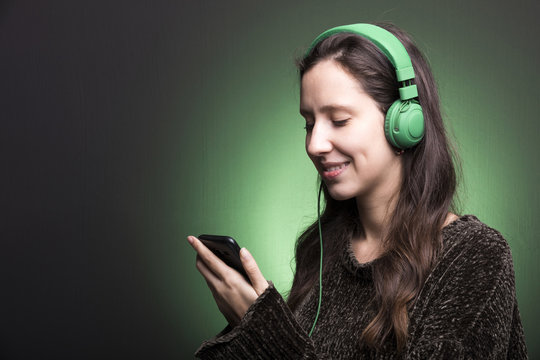 Young girl choosing a music on her smartphone to listen