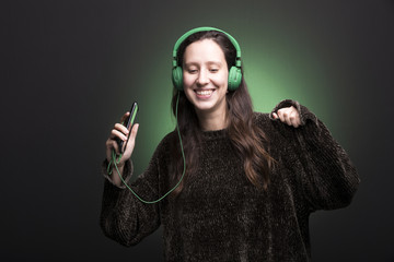 Portrait of a young girl listening music with green headphones