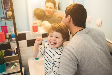 Young father with his son brushing teeth