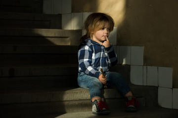 Boy with thinking face sit on house stairs