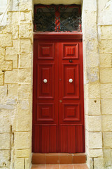 Traditional classic style wooden medieval vintage red painted door with knockers in Valletta, Malta.