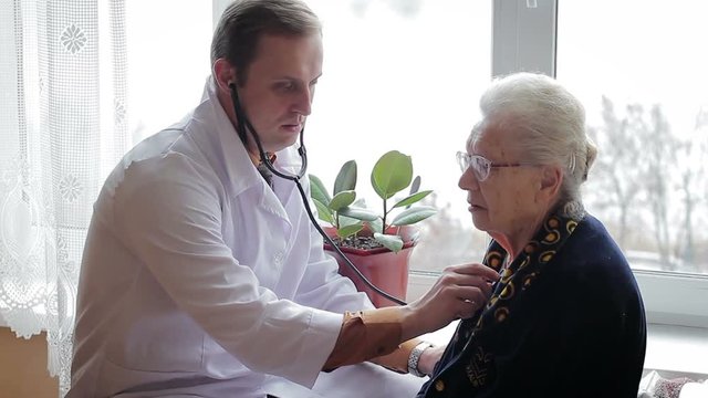 Doctor listening to the lungs of an old woman with a phonendoscope