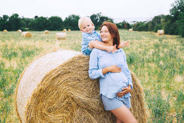 Pregnant woman and son on nature. Mother waiting of a second baby.