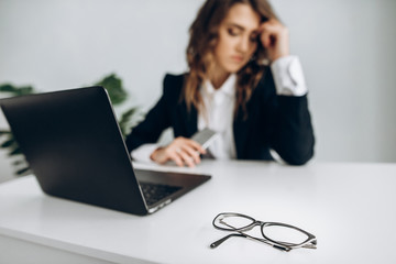 A hard working day of a business woman. Fatigue. Glasses lie on the table in the foreground