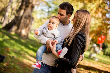 Fototapeta premium Happy young parents with baby boy in autumn park