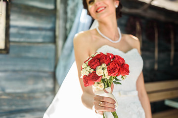 beautiful bride in white dress with bouquet of flowers on the street