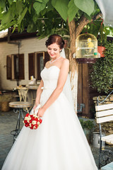 beautiful bride in white dress with bouquet of flowers on the street